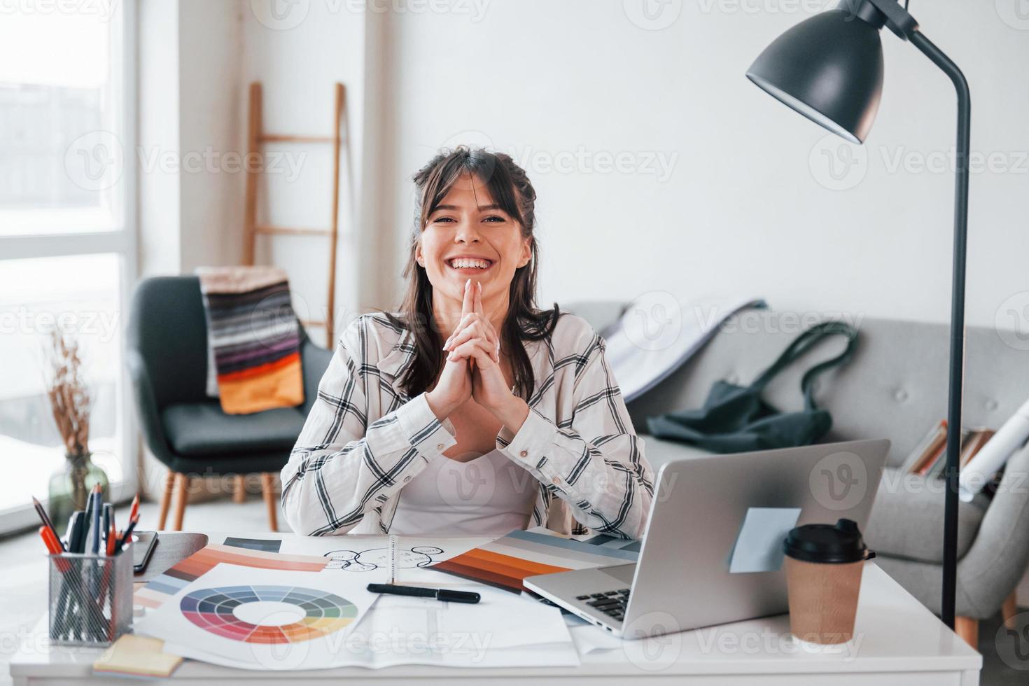 With laptop on the table. Young female freelance worker is indoors in home at daytime photo