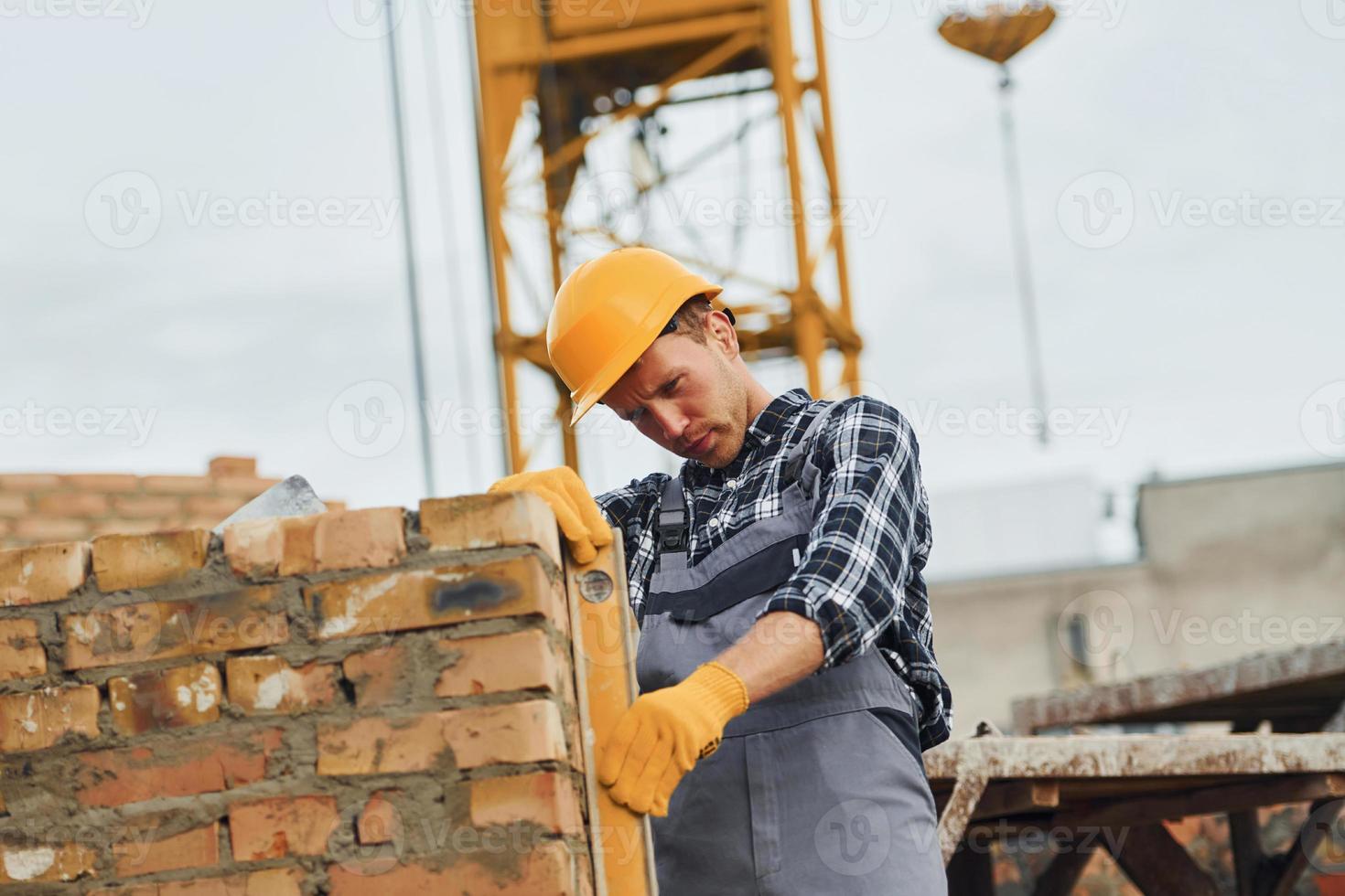 With level measuring tool. Construction worker in uniform and safety equipment have job on building photo