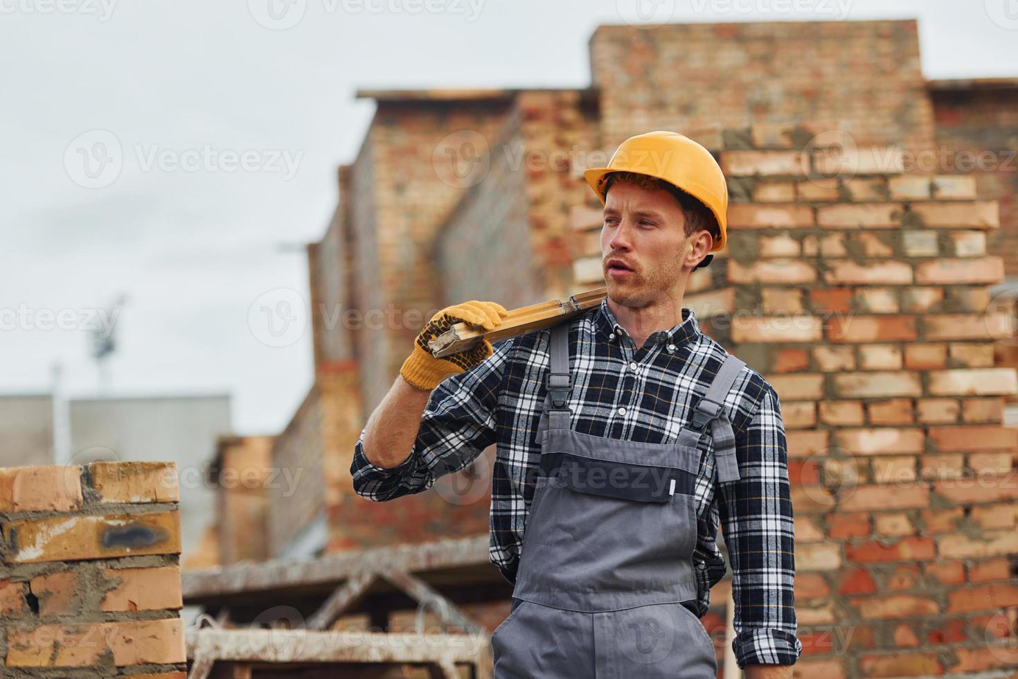 Holds measuring tool and takes break. Construction worker in uniform and safety equipment have job on building photo