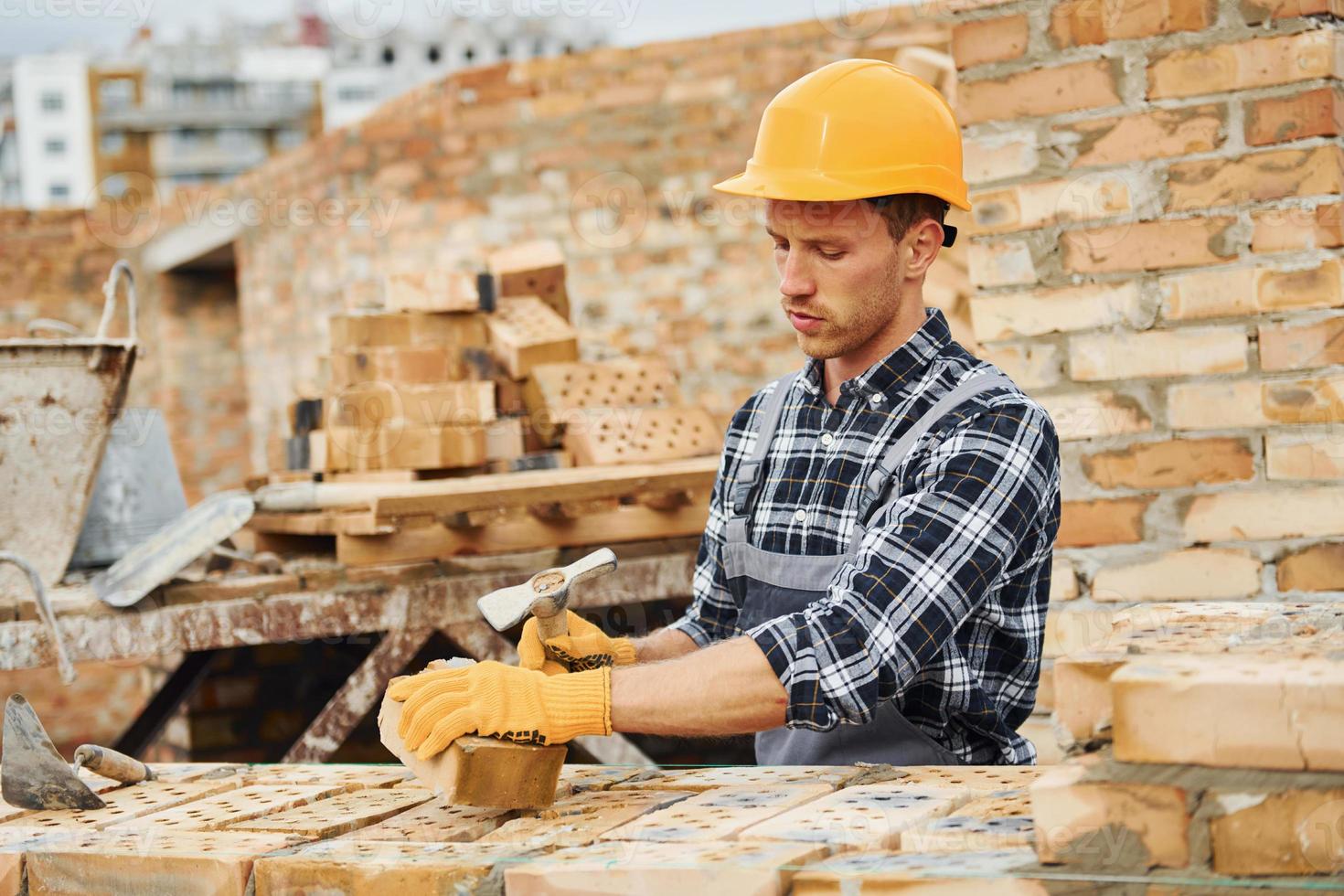 Laying bricks. Construction worker in uniform and safety equipment have job on building photo