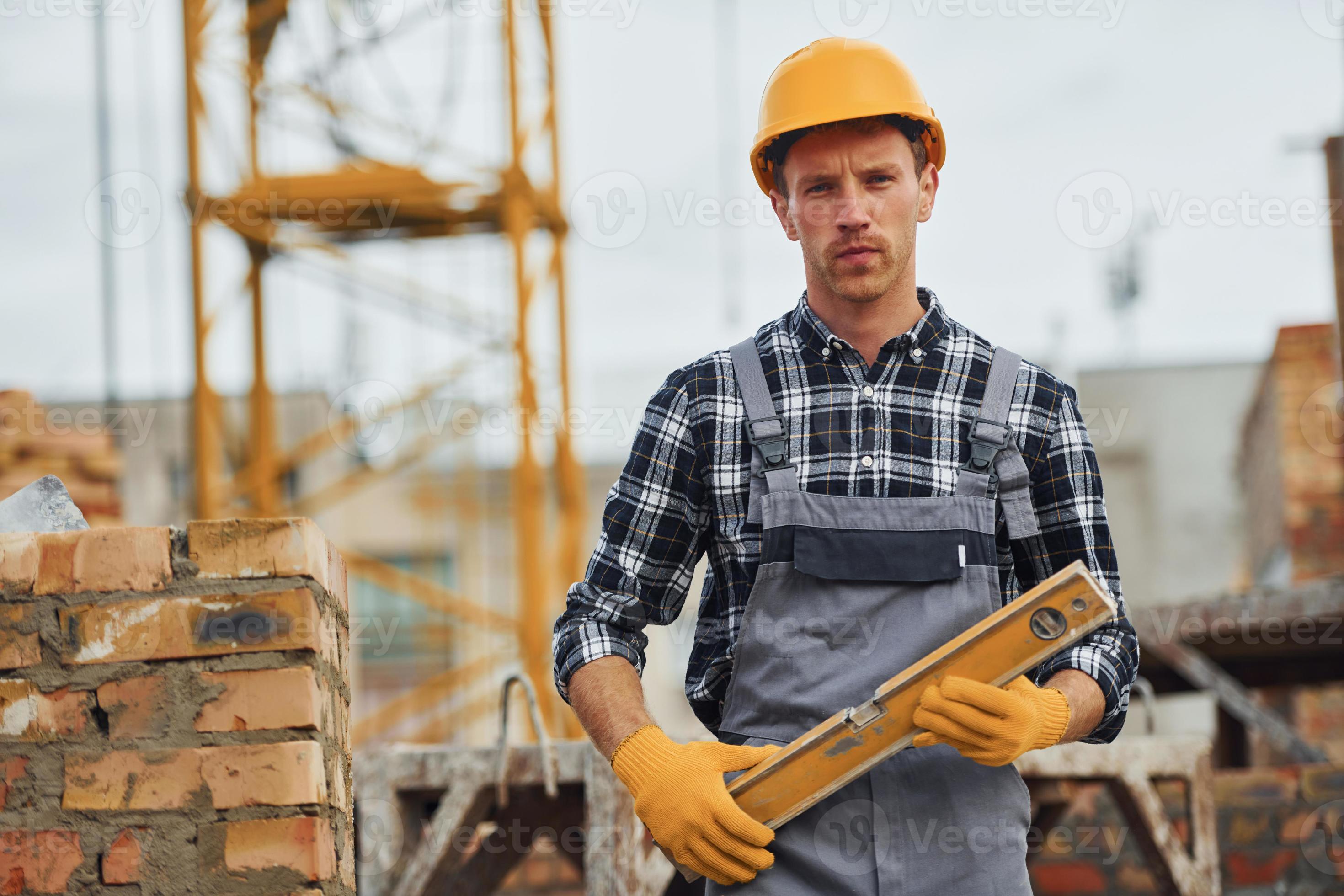 With level measuring tool. Construction worker in uniform and safety equipment have job on