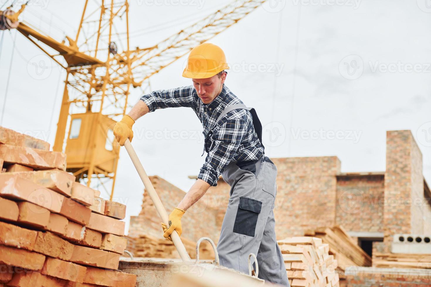 con pala en las manos. trabajador de la construcción en uniforme y equipo de seguridad tiene trabajo en la construcción foto