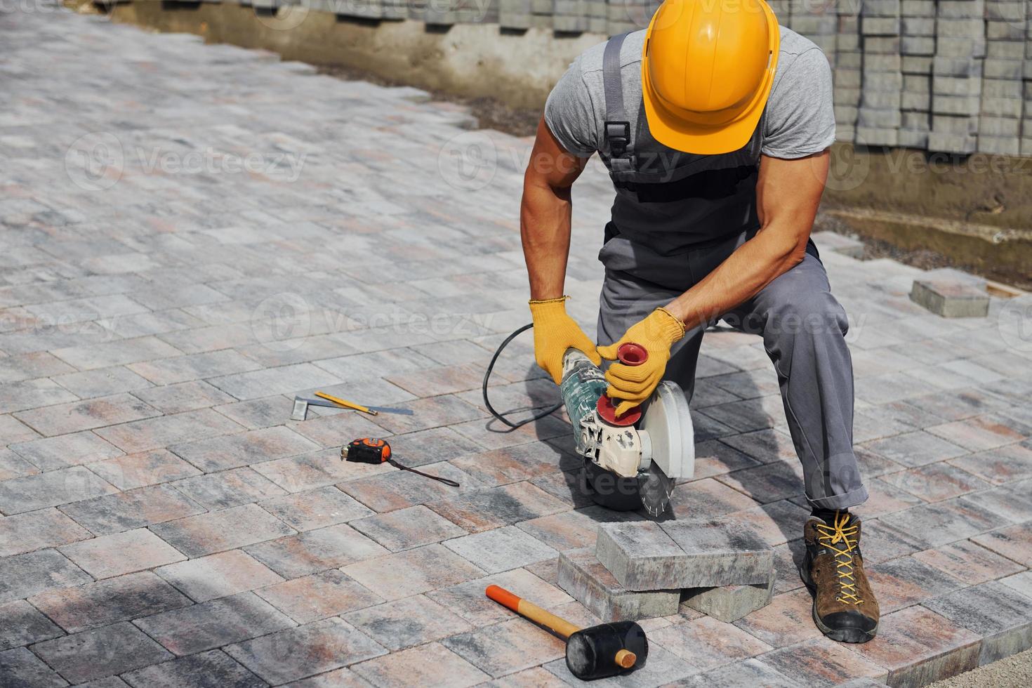 Male worker in yellow colored uniform have job with pavement photo