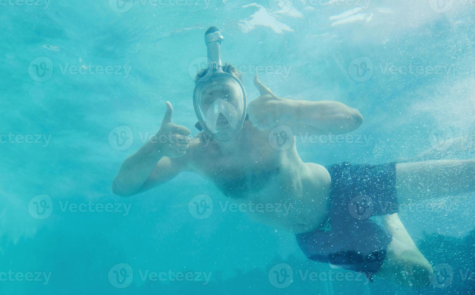Man swimming underwater in the pool at daytime. Having fun photo