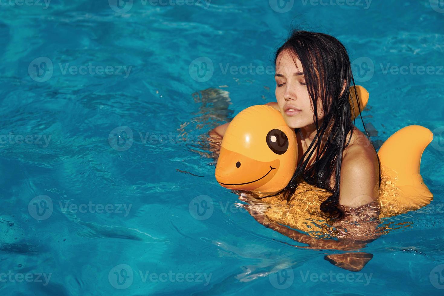 With yellow duck toy. Girl have fun and rest in swimming pool at daytime. Conception of vacation photo