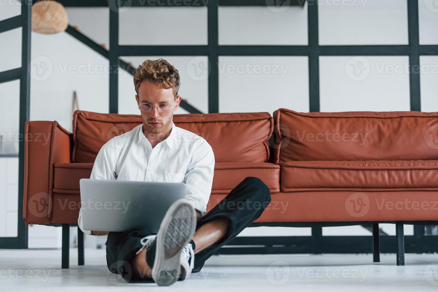 Having a rest. Caucasian young guy in elegant white shirt indoors at home photo