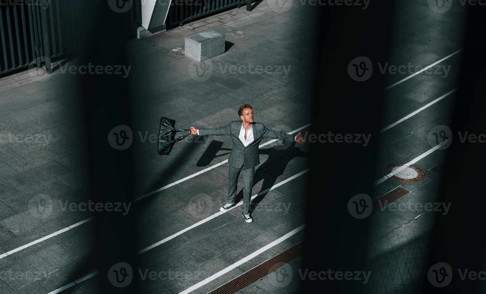 Celebrating success. Young businessman in grey formal wear is outdoors in the city photo