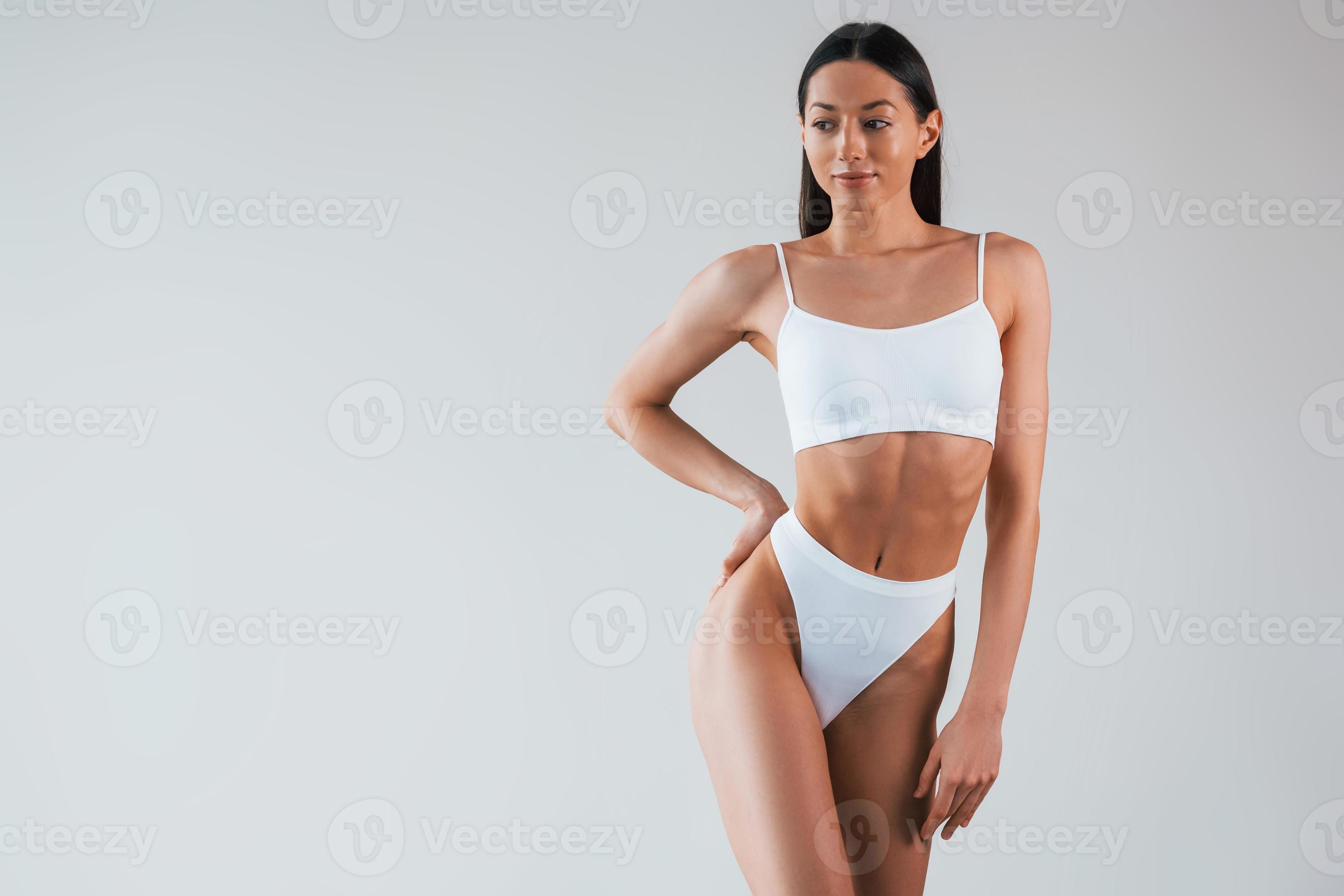 In white underwear. Woman with sportive slim body type that is in