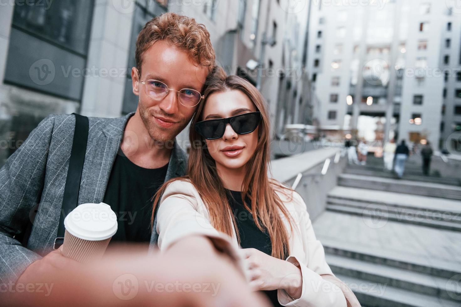 Makes selfie. Woman and man in the town at daytime. Well dressed people photo