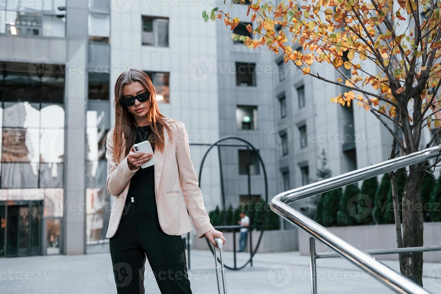 Town style clothes. Beautiful young european woman is outdoors in the city at daytime photo