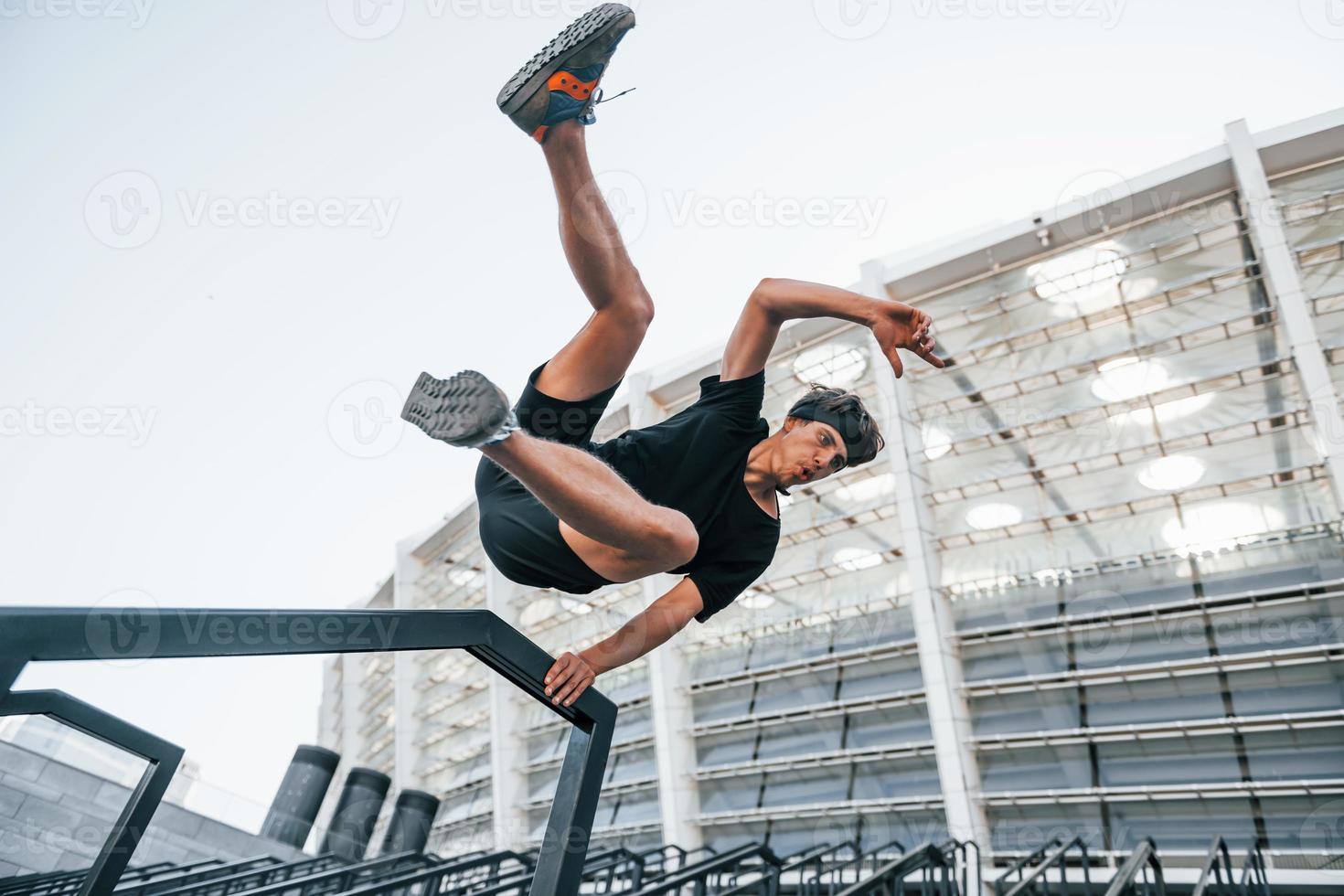 hace parkour. un joven con ropa deportiva hace ejercicio al aire libre durante el día foto