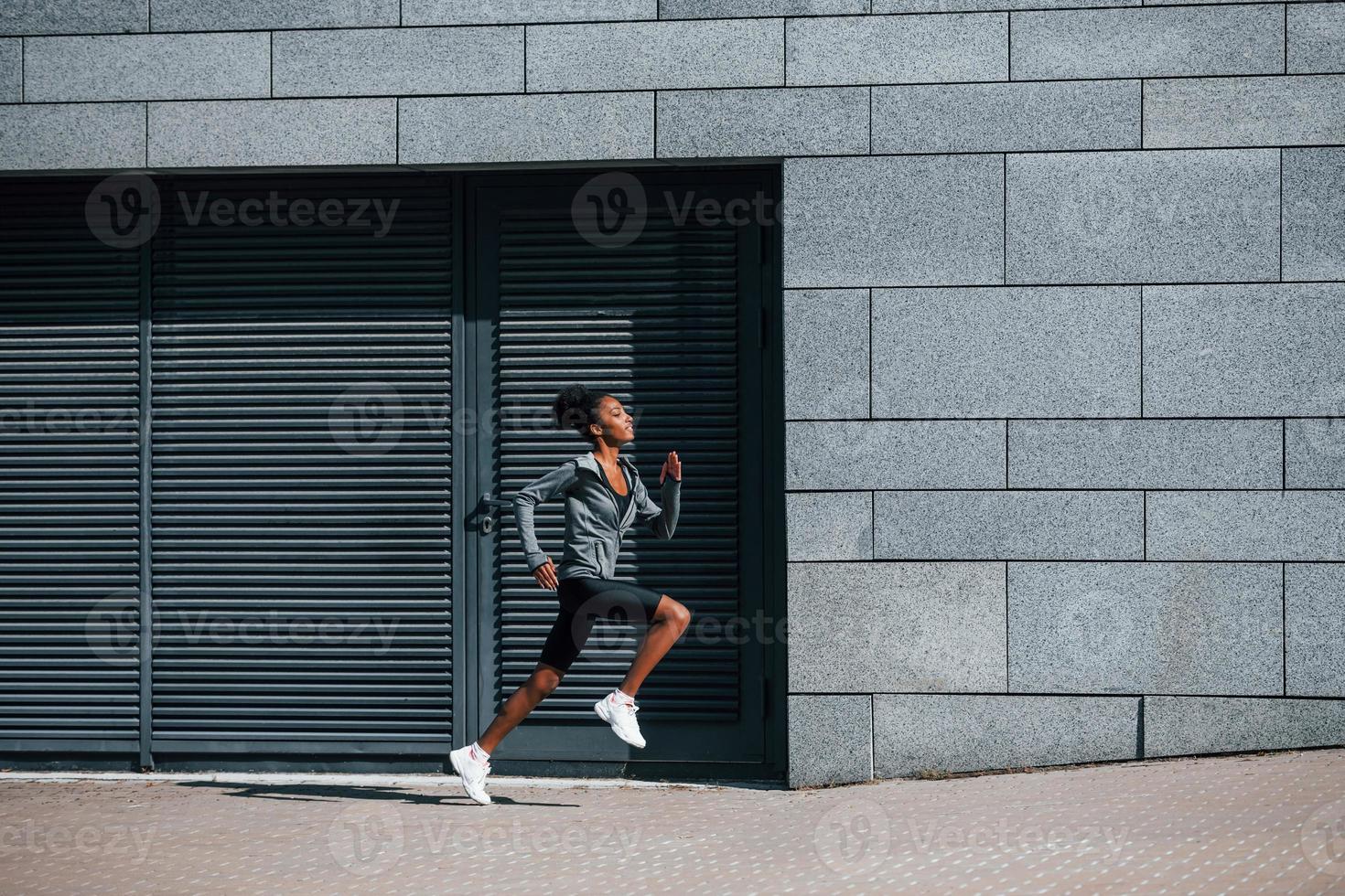 Active runner. Young african american woman in sportive clothes have workout outdoors at daytime photo