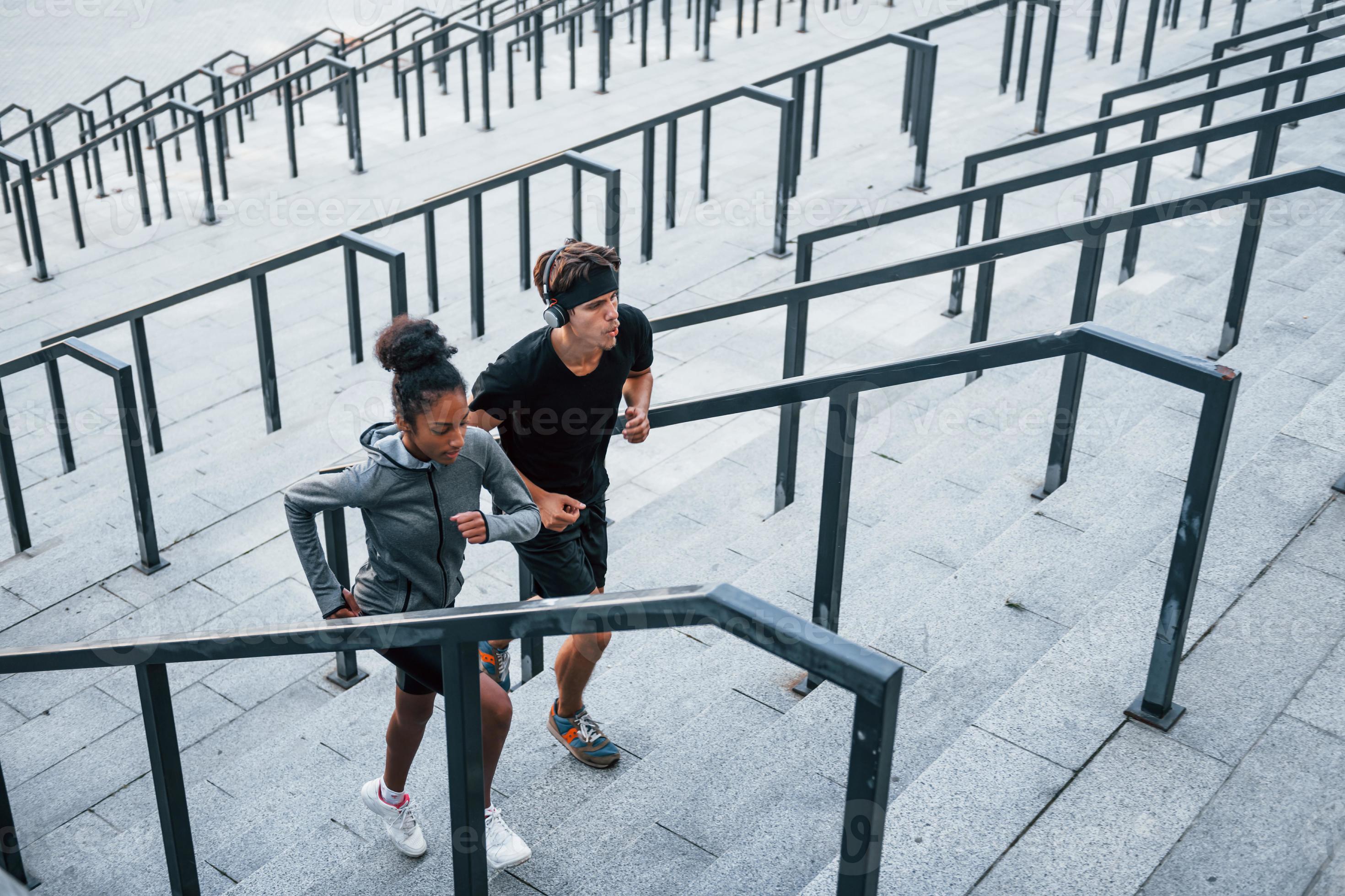 Running on bleachers. European man and african american woman in