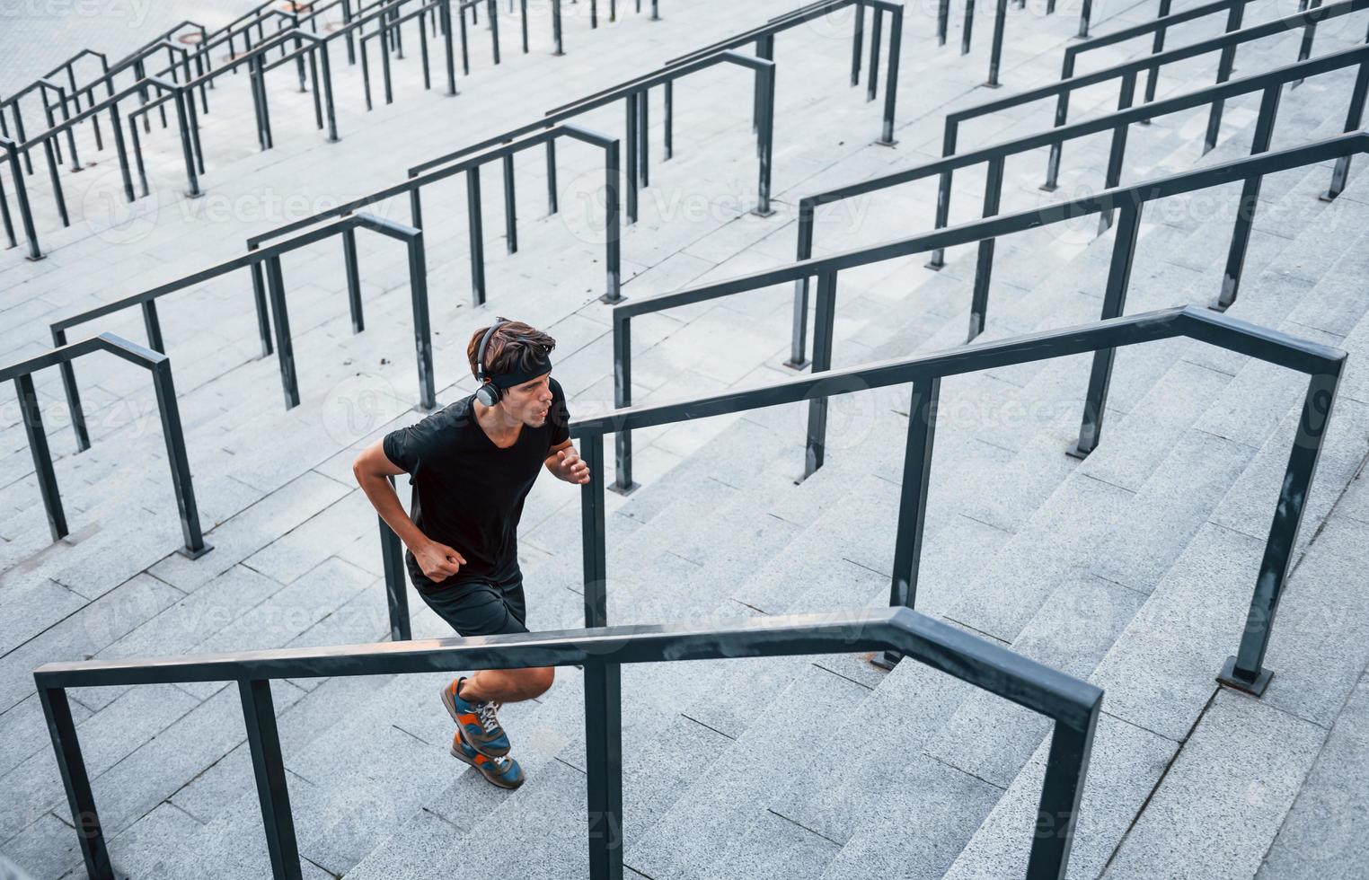 Running and jumping. Young man in sportive clothes have workout outdoors at daytime photo