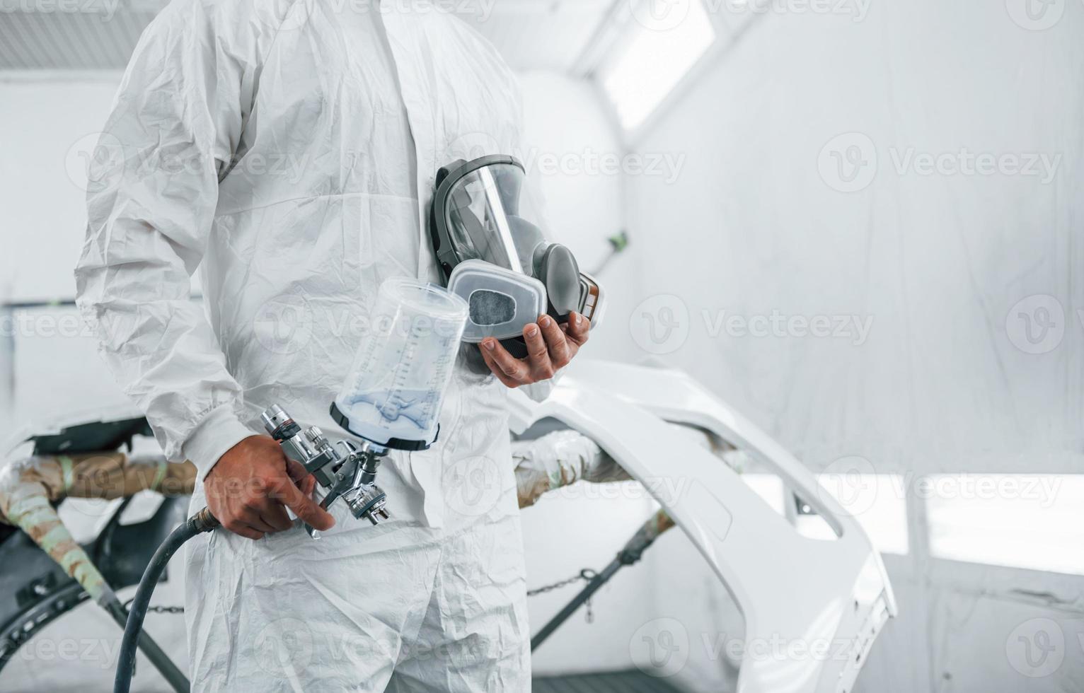 Close up view. Caucasian automobile repairman in uniform works in garage photo