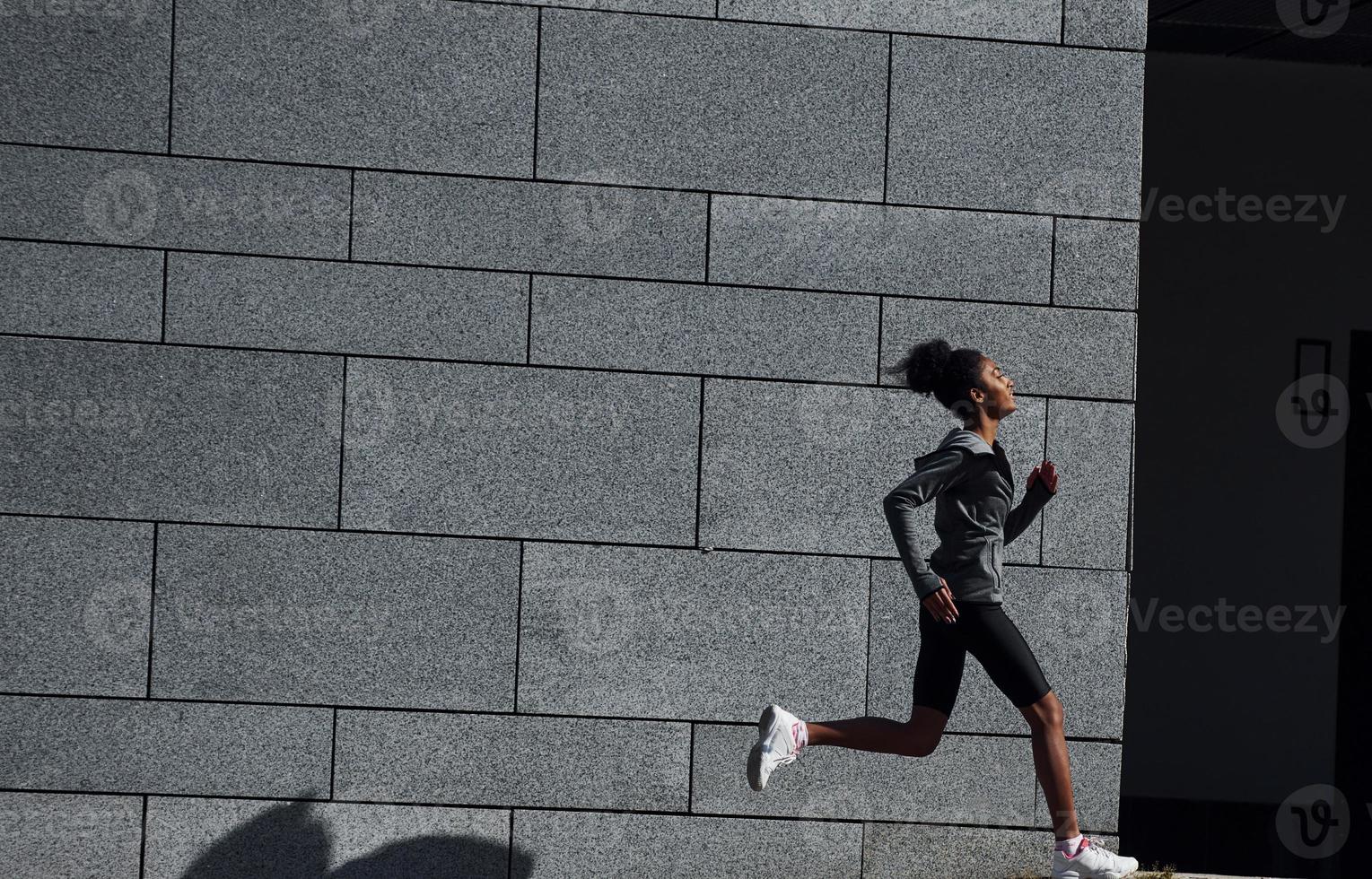 Active runner. Young african american woman in sportive clothes have workout outdoors at daytime photo