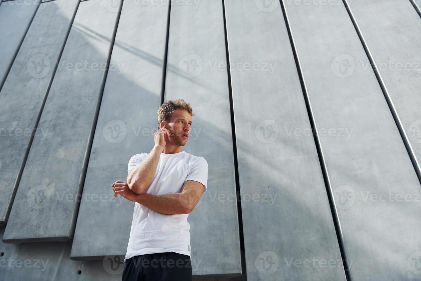 contra el exterior del edificio. un joven con ropa deportiva hace ejercicio al aire libre durante el día foto