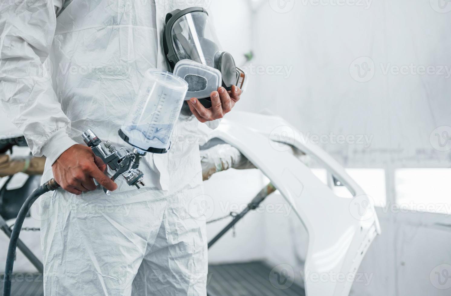 Close up view. Caucasian automobile repairman in uniform works in garage photo