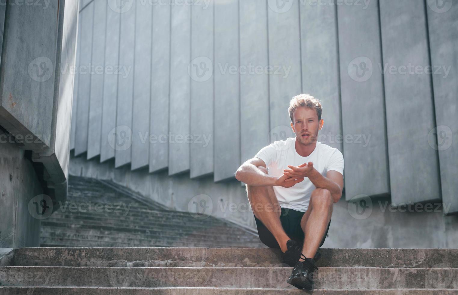 Takes a break. Young man in sportive clothes have workout outdoors at daytime photo