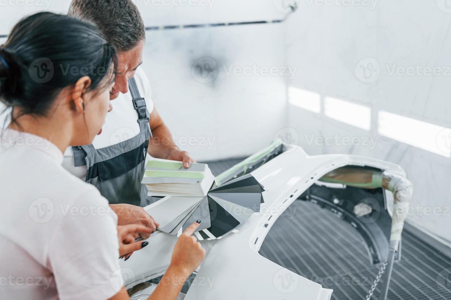 Young woman with man works together in automobile repair garage photo