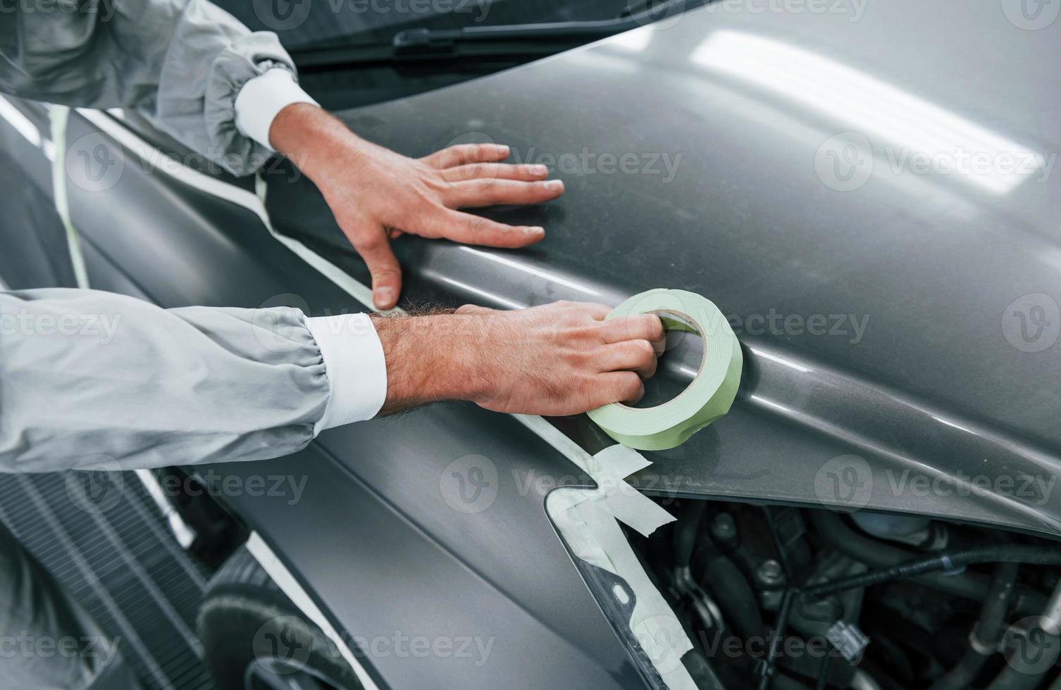 Detailed work. Caucasian automobile repairman in uniform have job in garage photo