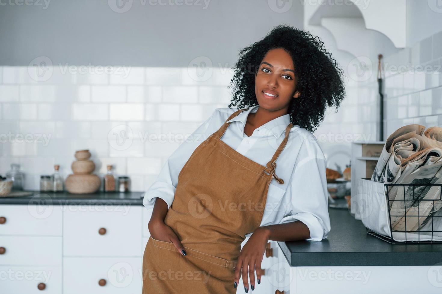 On the kitchen. Young african american woman with curly hair indoors at home photo