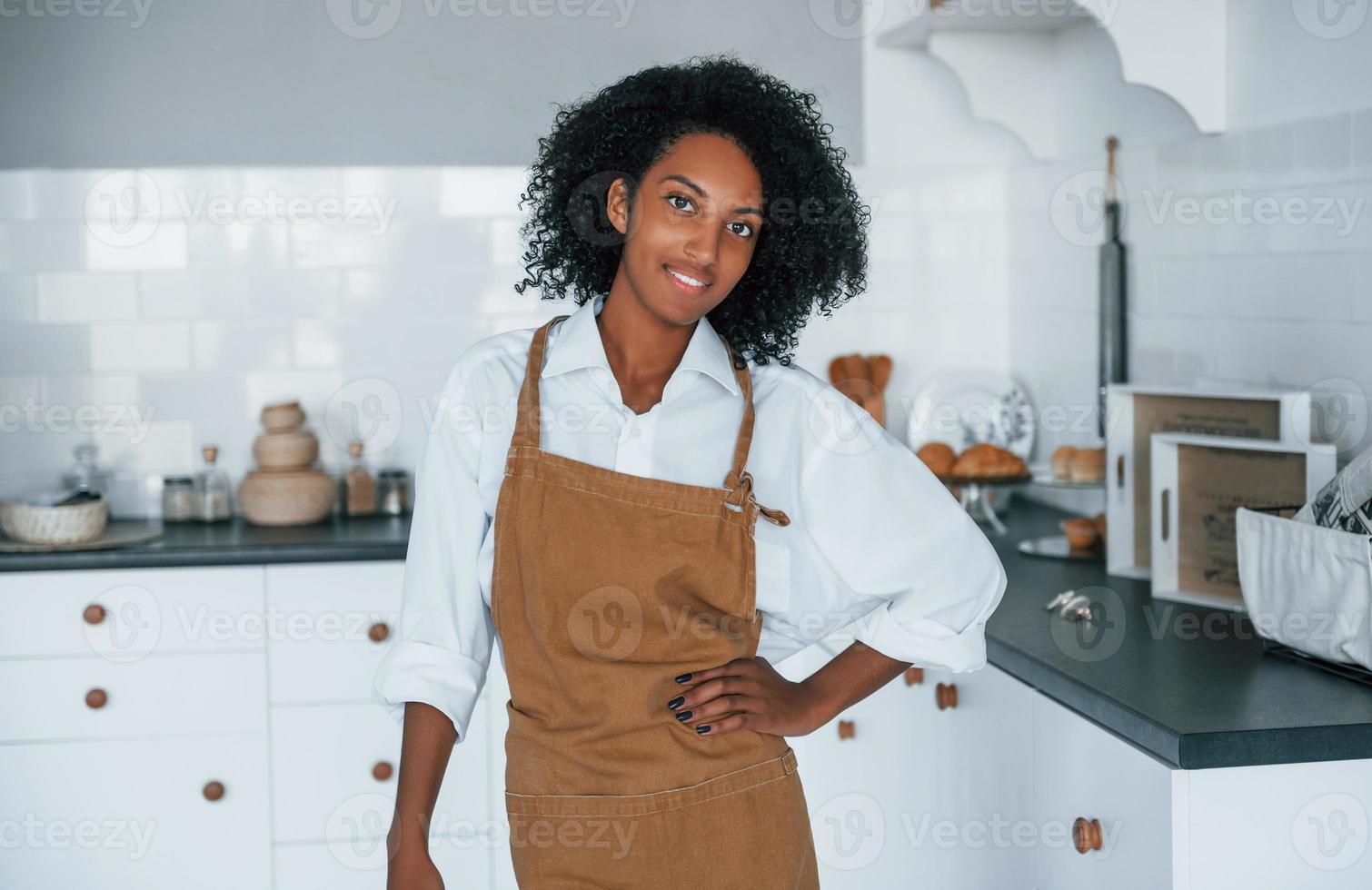 On the kitchen. Young african american woman with curly hair indoors at home photo