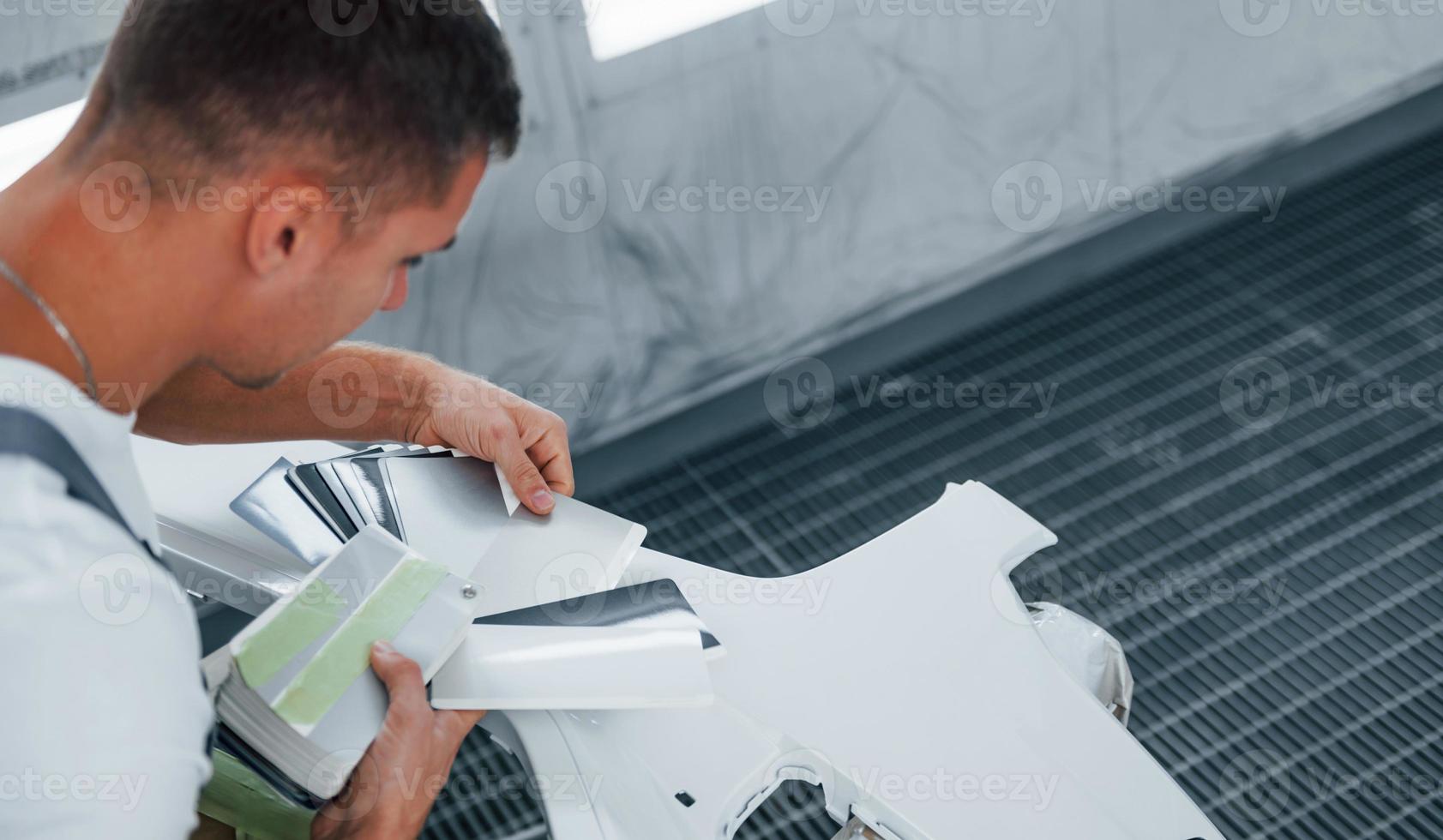 Detailed work. Caucasian automobile repairman in uniform have job in garage photo