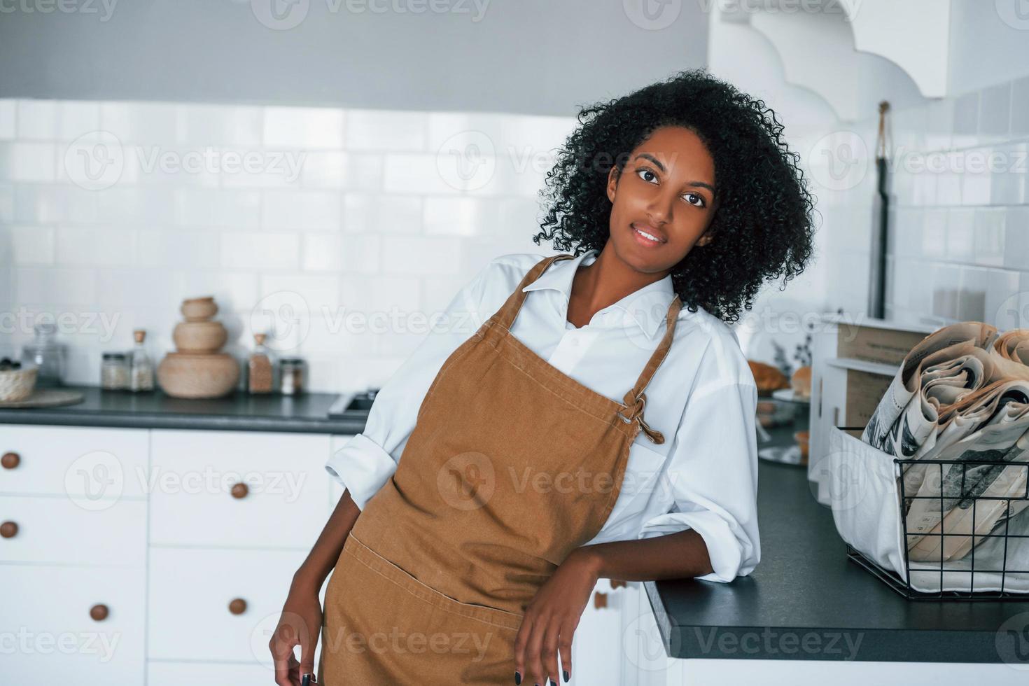 On the kitchen. Young african american woman with curly hair indoors at home photo