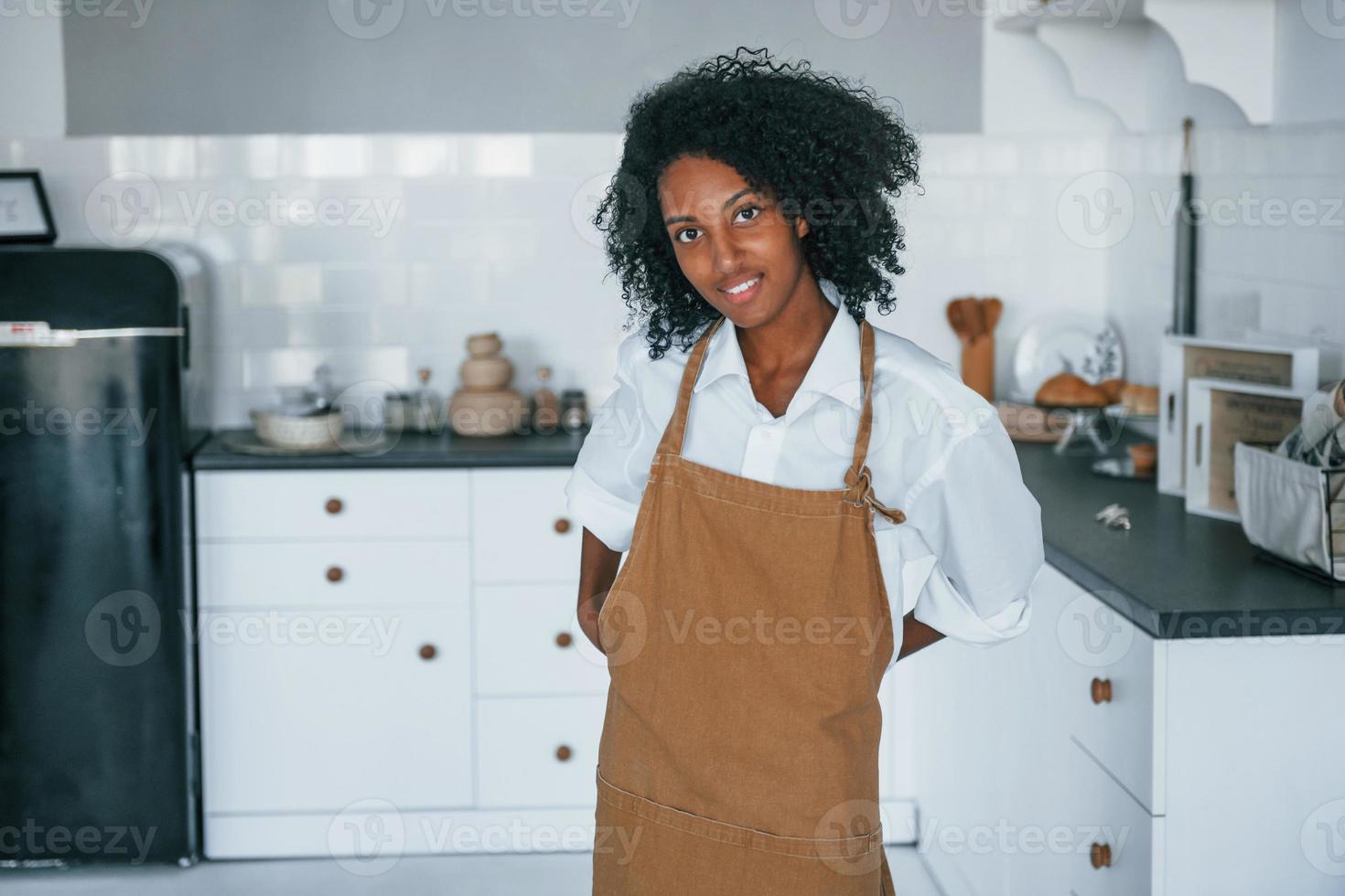 On the kitchen. Young african american woman with curly hair indoors at home photo