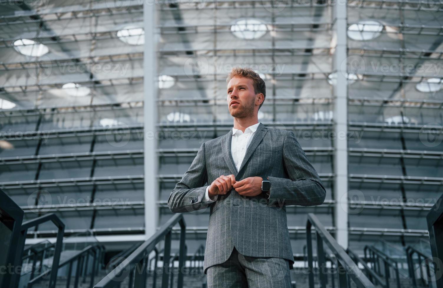 en las escaleras del estadio. un joven hombre de negocios con ropa formal gris está al aire libre en la ciudad foto