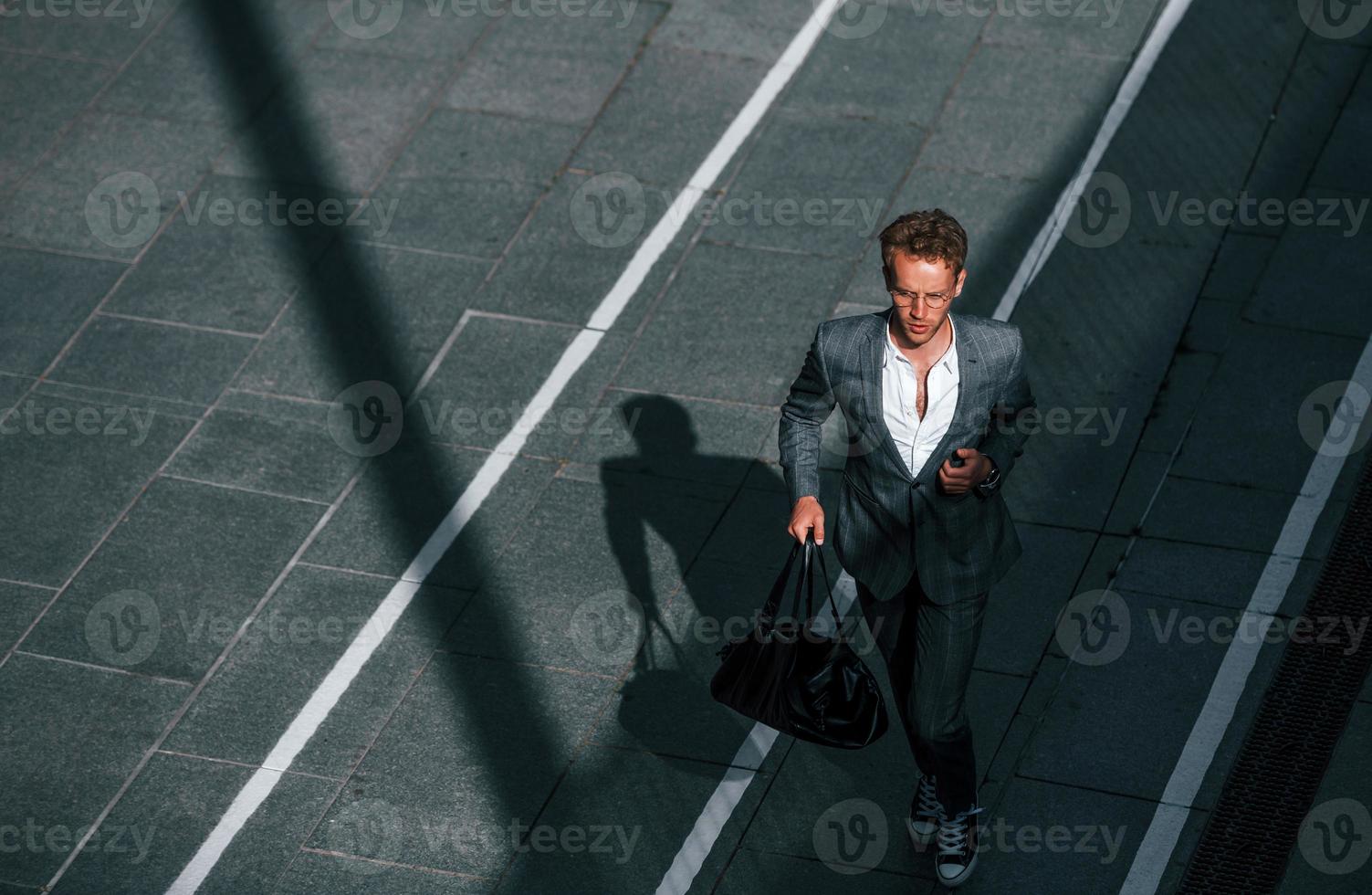 View from the top. Young businessman in grey formal wear is outdoors in the city photo