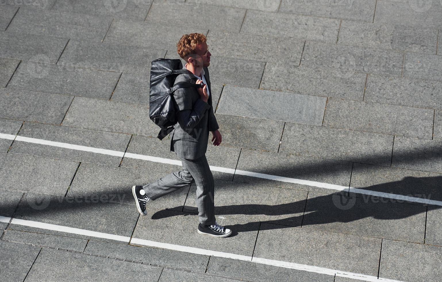 Walks on the road. Young businessman in grey formal wear is outdoors in the city photo