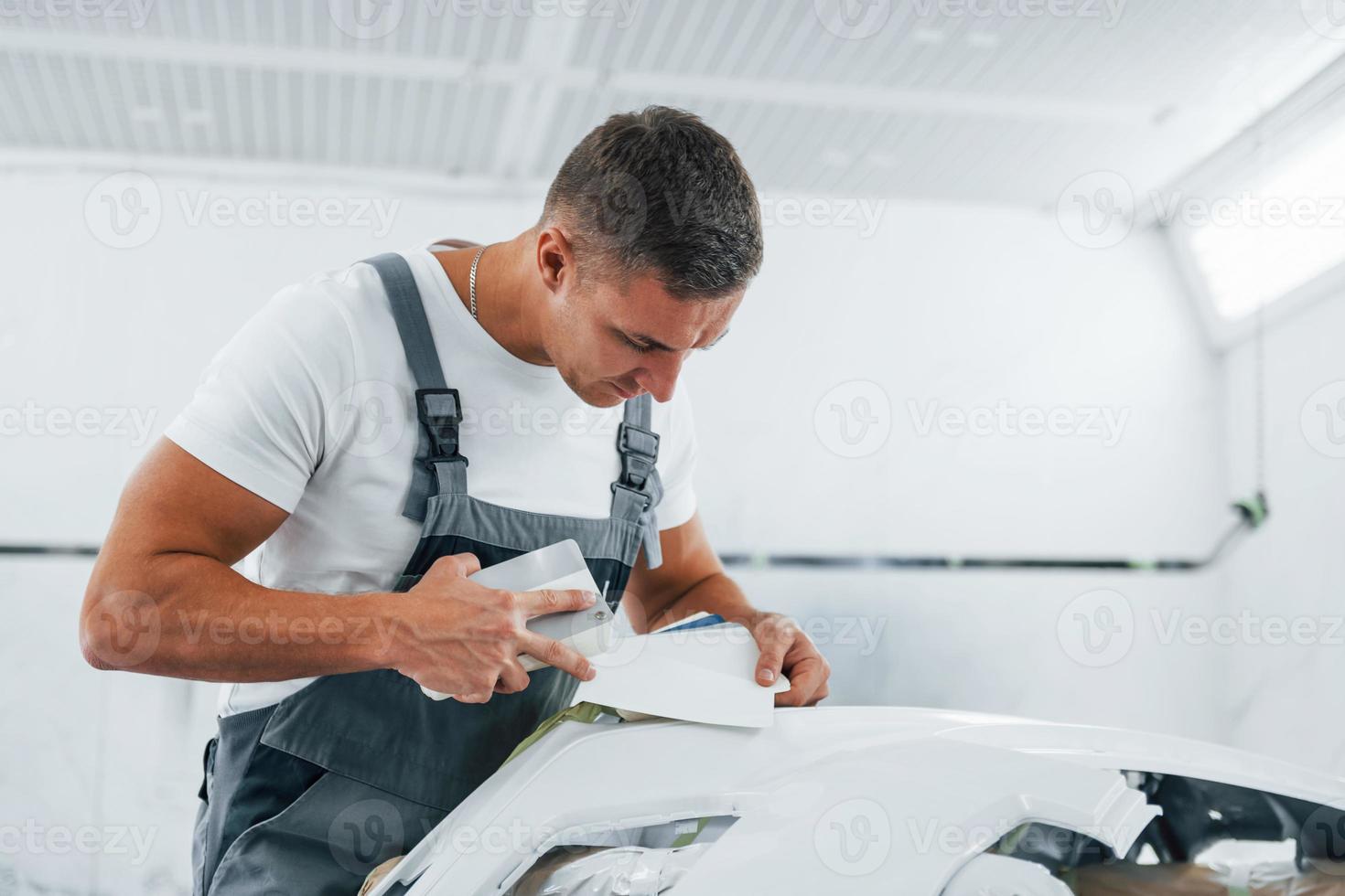 trabajo detallado. reparador de automóviles caucásico en uniforme tiene trabajo en el garaje foto