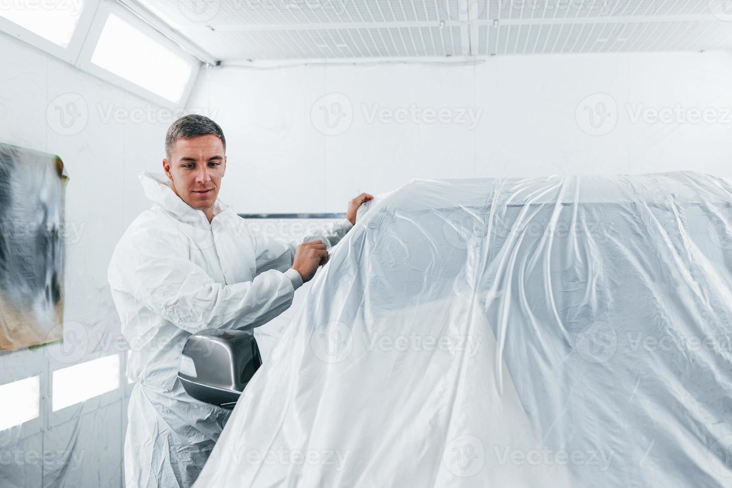 Caucasian automobile repairman in uniform works in garage photo