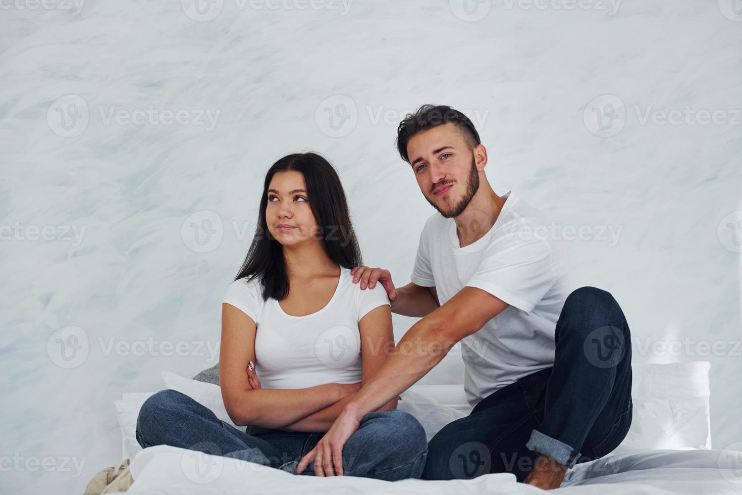 Offended young woman sits on the bed with her boyfriend at home photo