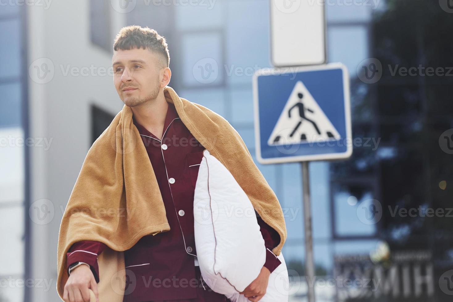 Young man in pajama is outdoors on the street. Feels sleepy photo