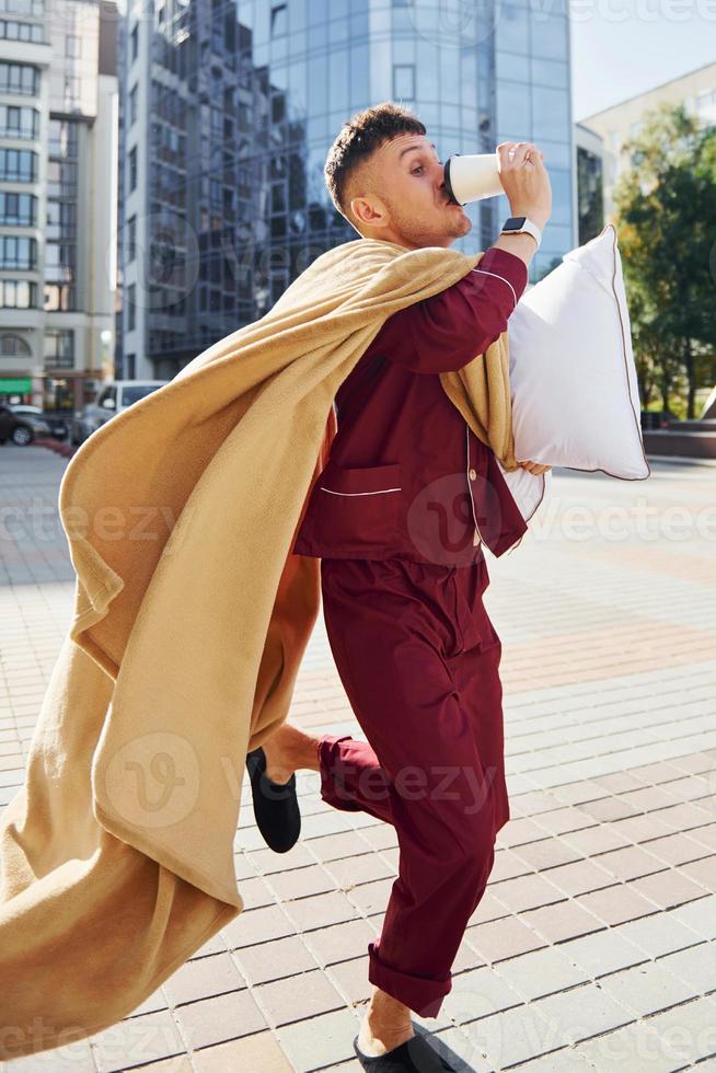 corriendo, tarde para el trabajo. joven en pijama está al aire libre en la calle. se siente somnoliento foto