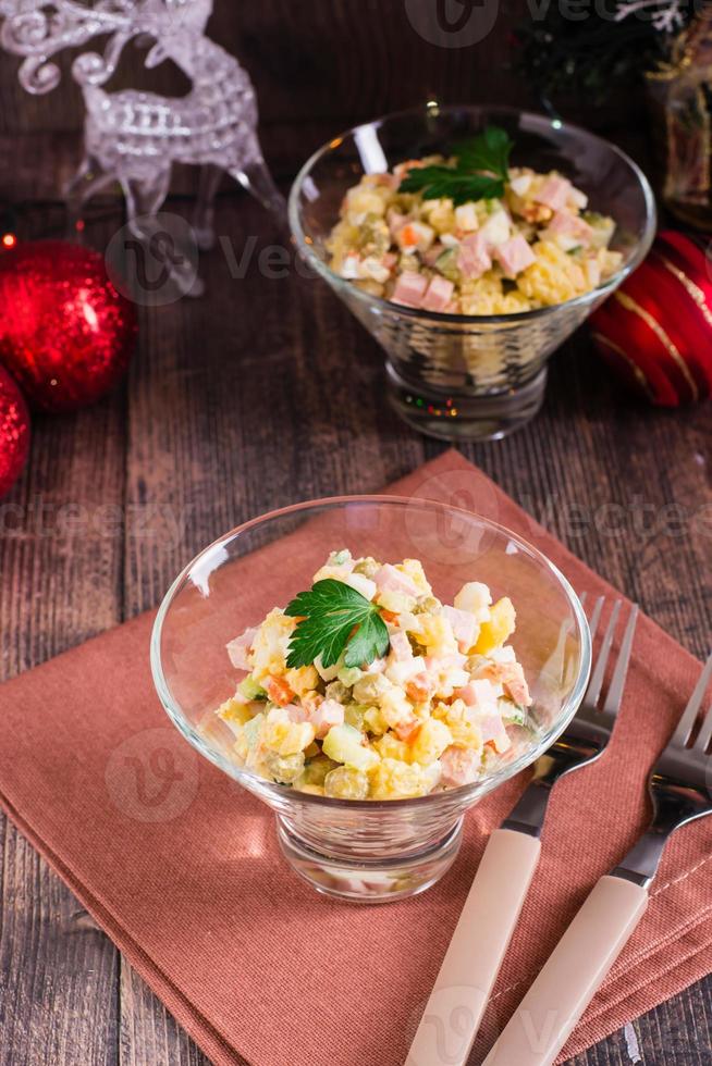 Olivier salad in bowls and Christmas decorations on a wooden table. Vertical view photo