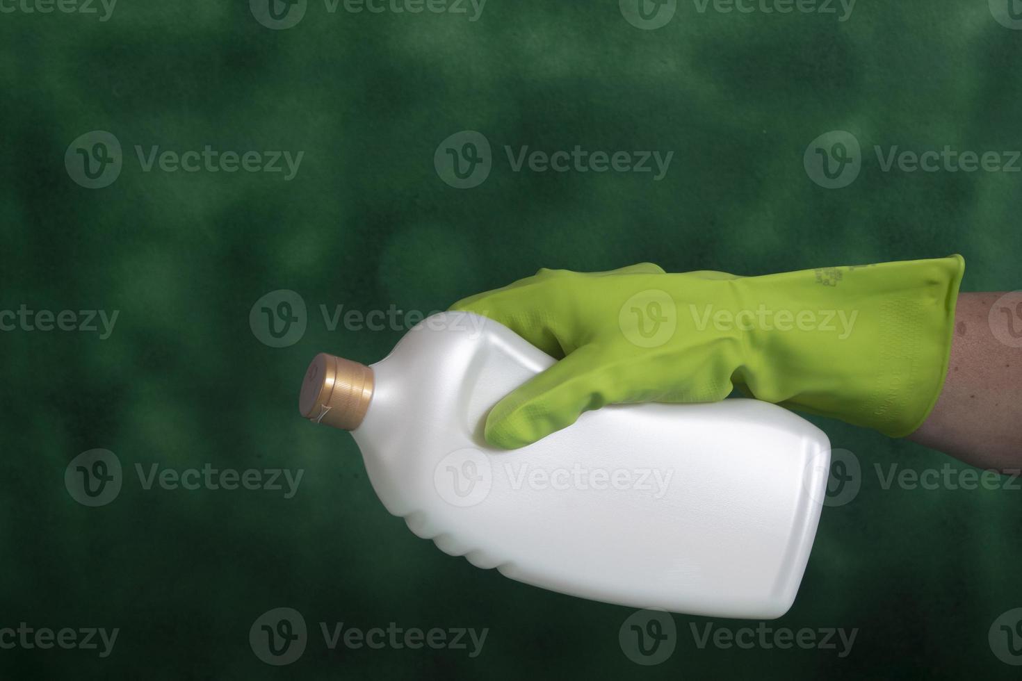 hand with protective glove holding packaging of cleaning products used for home hygiene photo