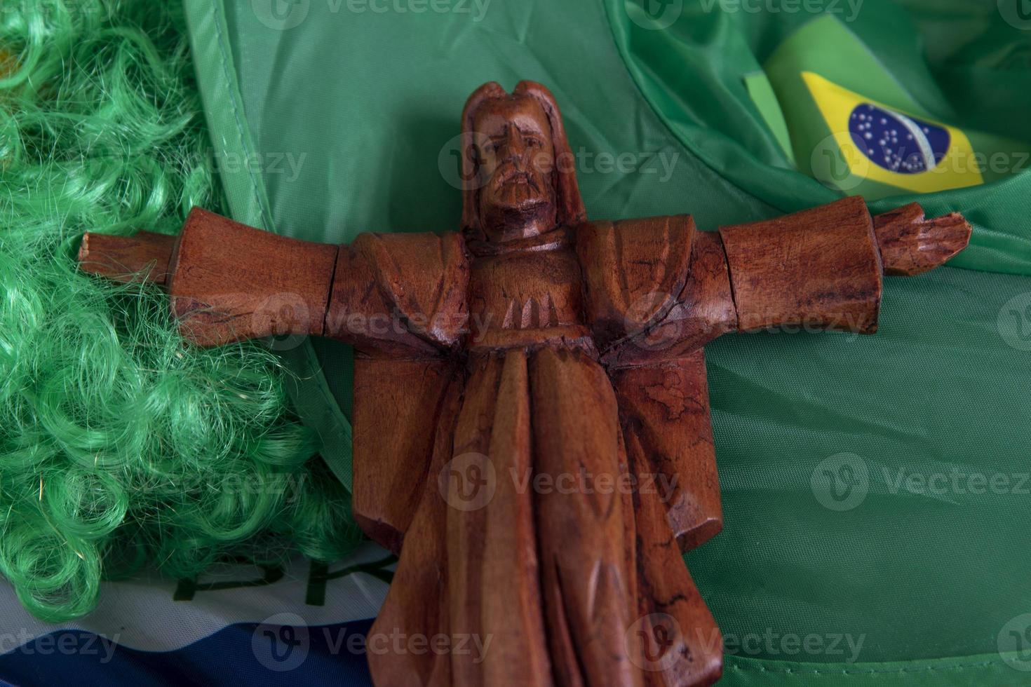 flag of Brazil in a wave filling the frame and a green and yellow wig with a protective saint photo