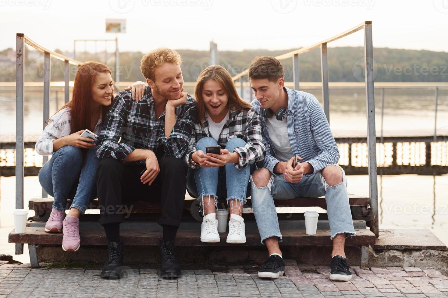 Near the lake. Group of young cheerful friends that is outdoors having fun together photo