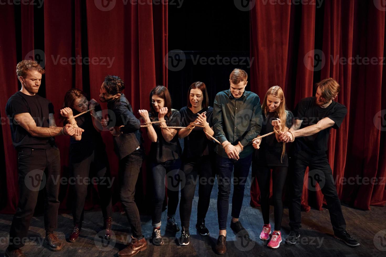 With rope in hands. Group of actors in dark colored clothes on rehearsal in the theater photo