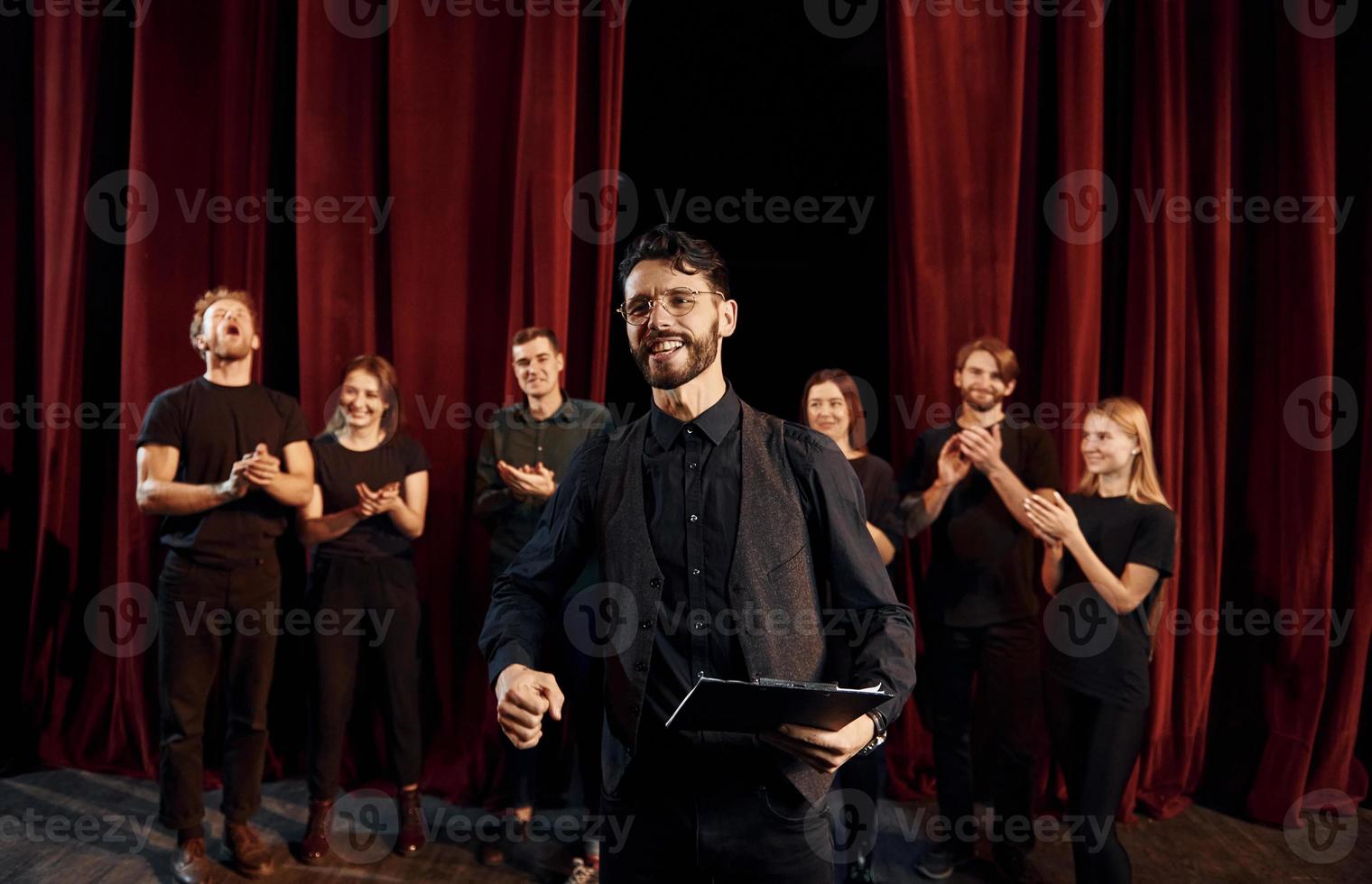 Man is practicing his role. Group of actors in dark colored clothes on rehearsal in the theater photo