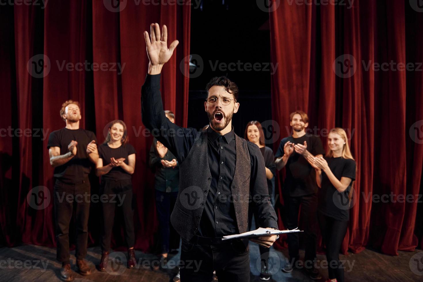 Man is practicing his role. Group of actors in dark colored clothes on rehearsal in the theater photo