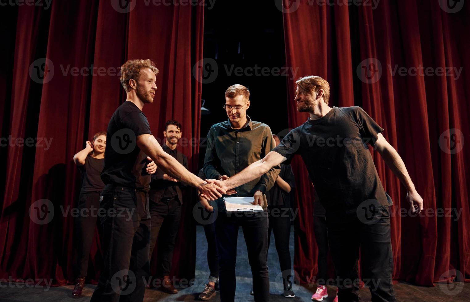 Working together. Group of actors in dark colored clothes on rehearsal in the theater photo