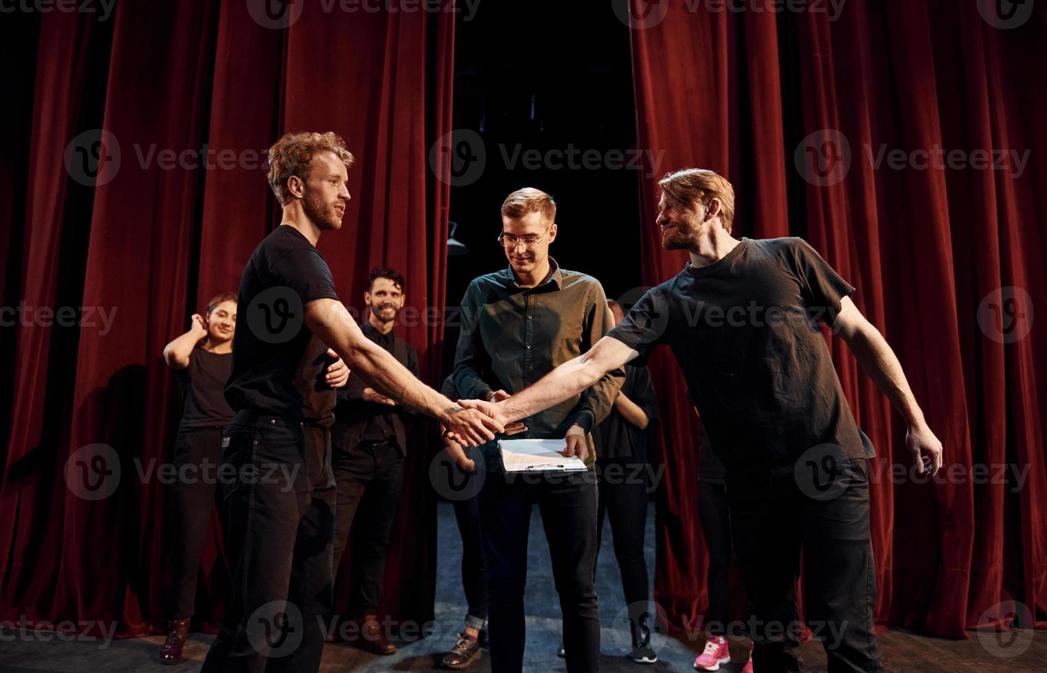 trabajando juntos. grupo de actores con ropa de color oscuro ensayando en el teatro foto