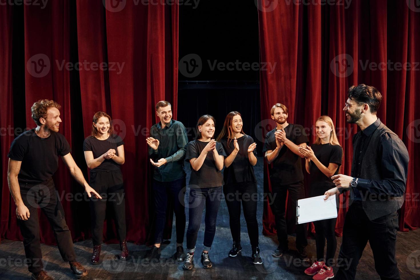 Man is practicing his role. Group of actors in dark colored clothes on rehearsal in the theater photo
