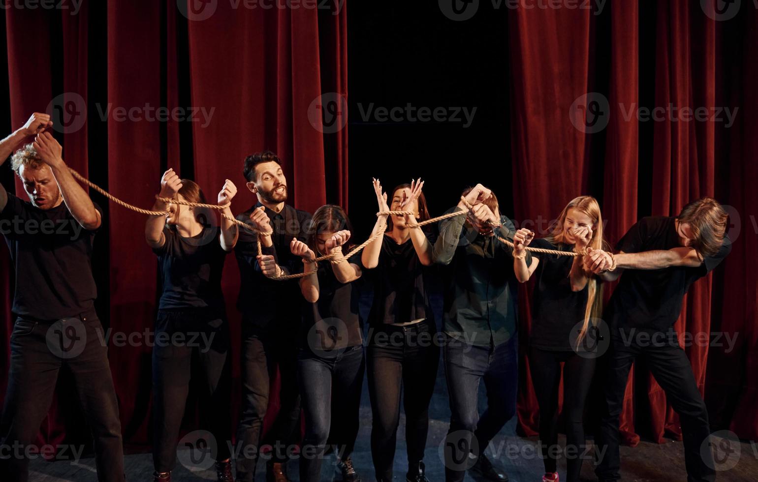 Knot in the hands. Group of actors in dark colored clothes on rehearsal in the theater photo