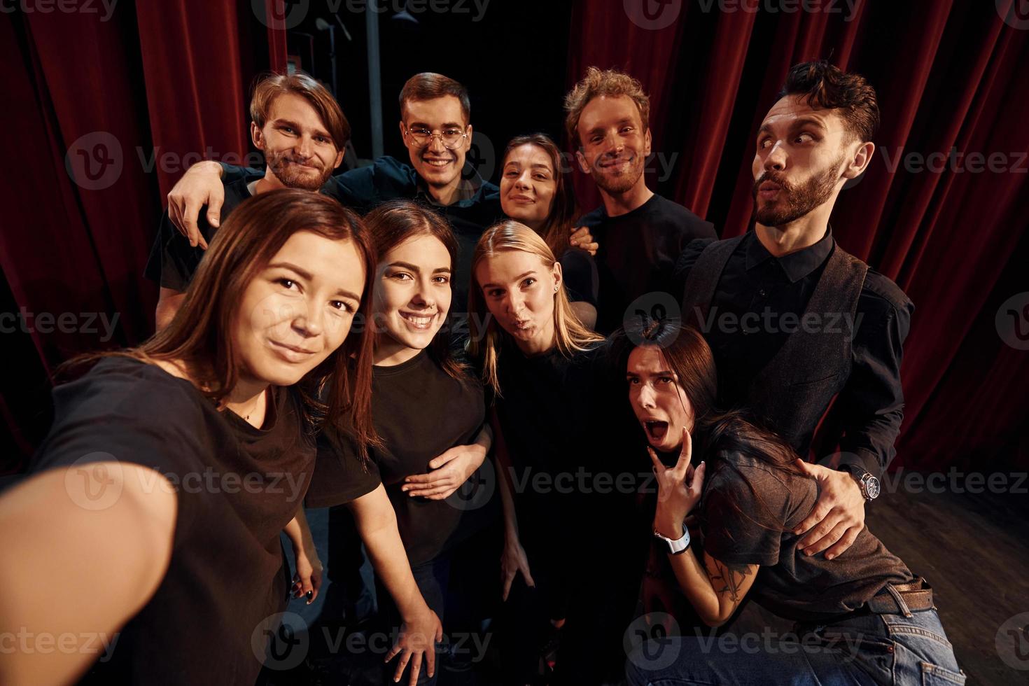 Making selfie. Group of actors in dark colored clothes on rehearsal in the theater photo